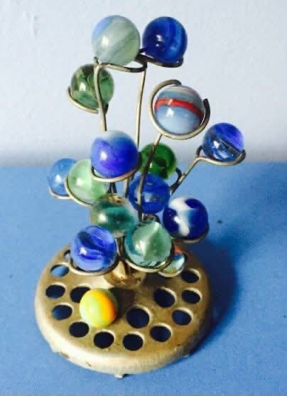 Colored marbles on curled wires in a brass flower frog