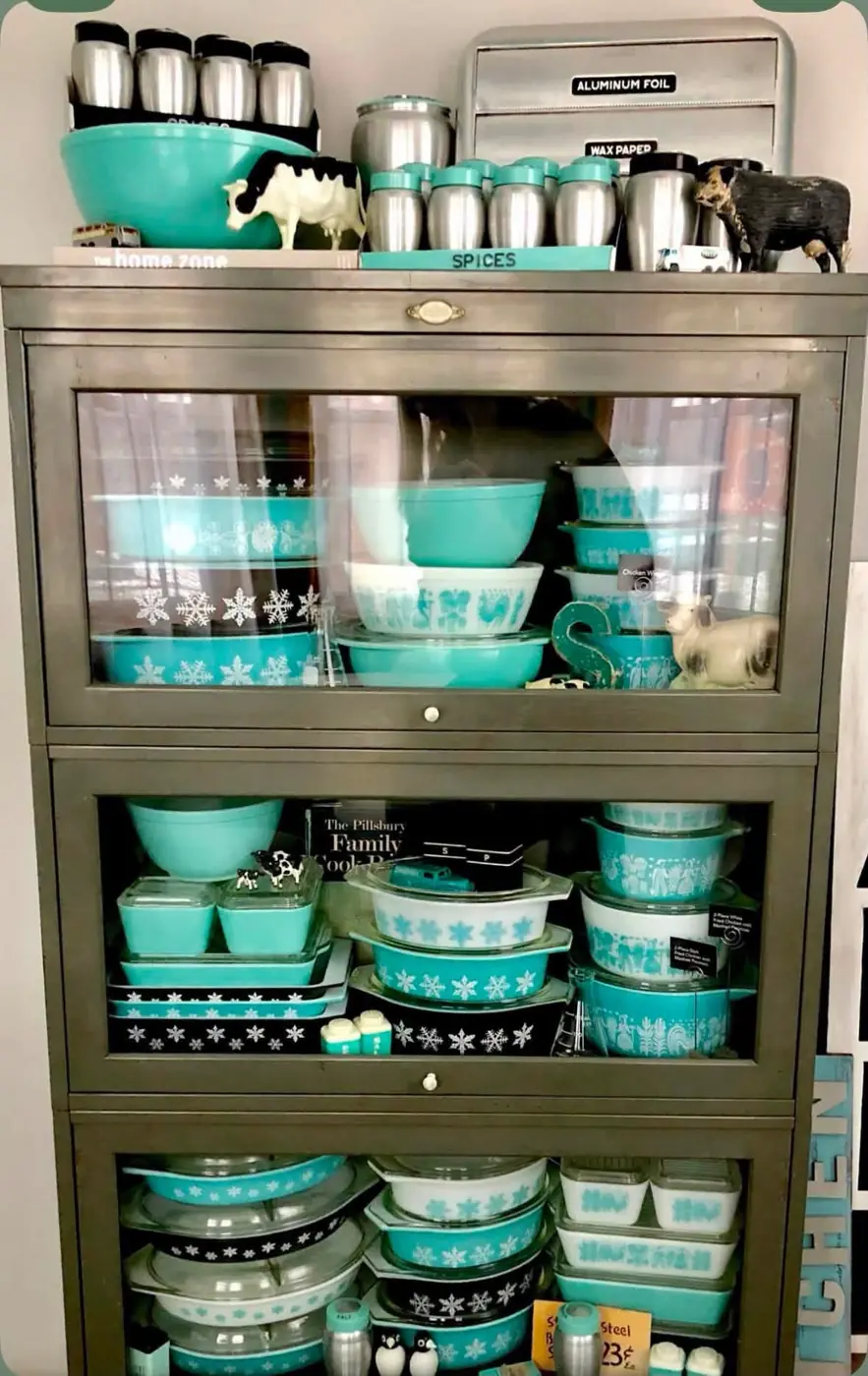 Turquoise Pyrex and kitchen accessories in a glass-front cabinet