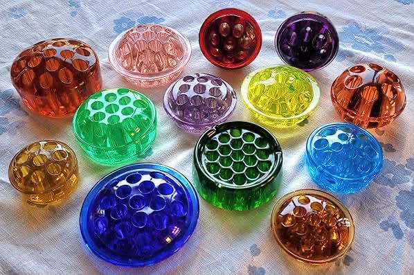 Colorful glass flower frogs arranged on a white cloth