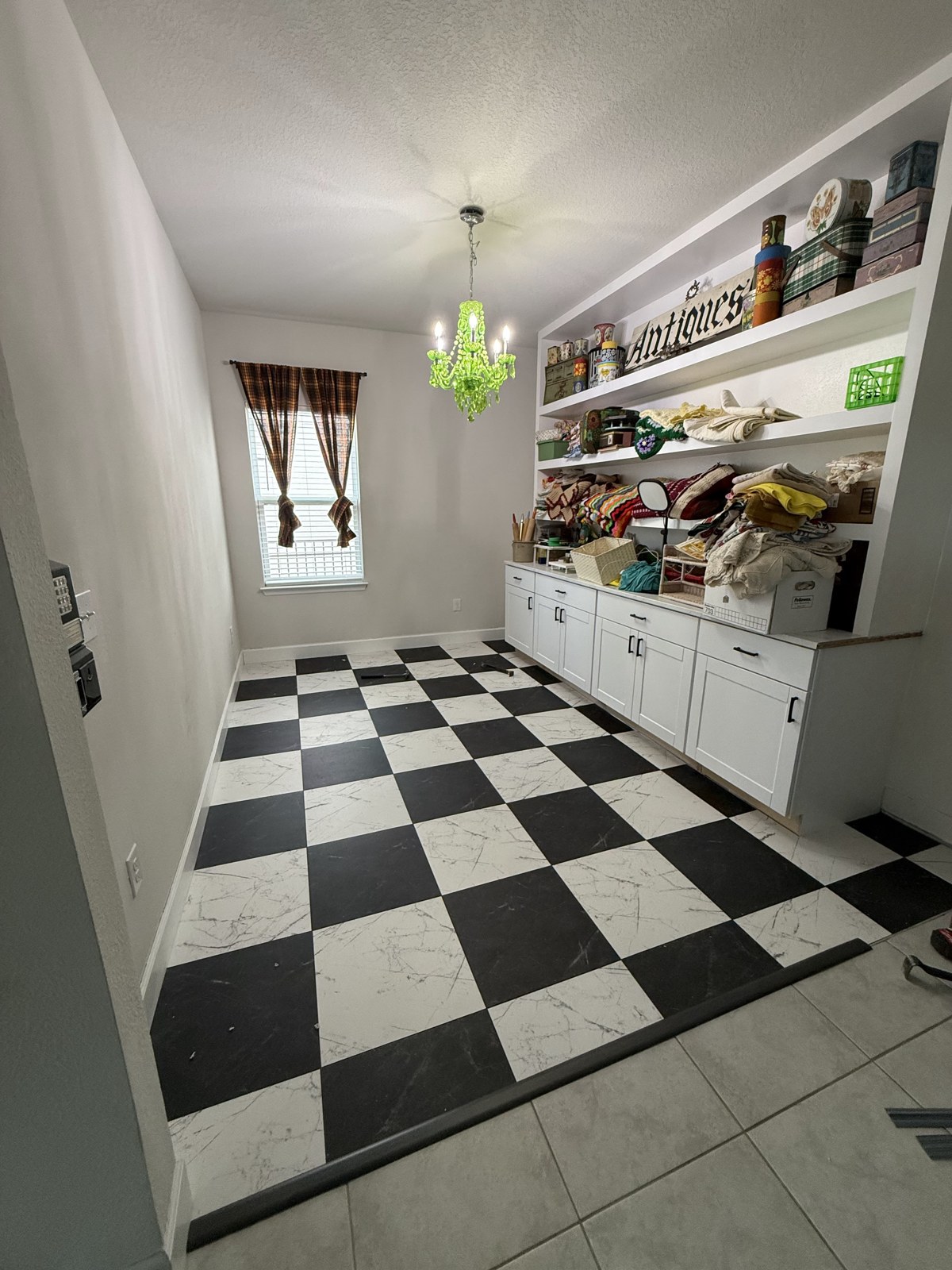 New black-and-white checkered flooring in the Whatnot room beneath the green chandelier and custom shelves