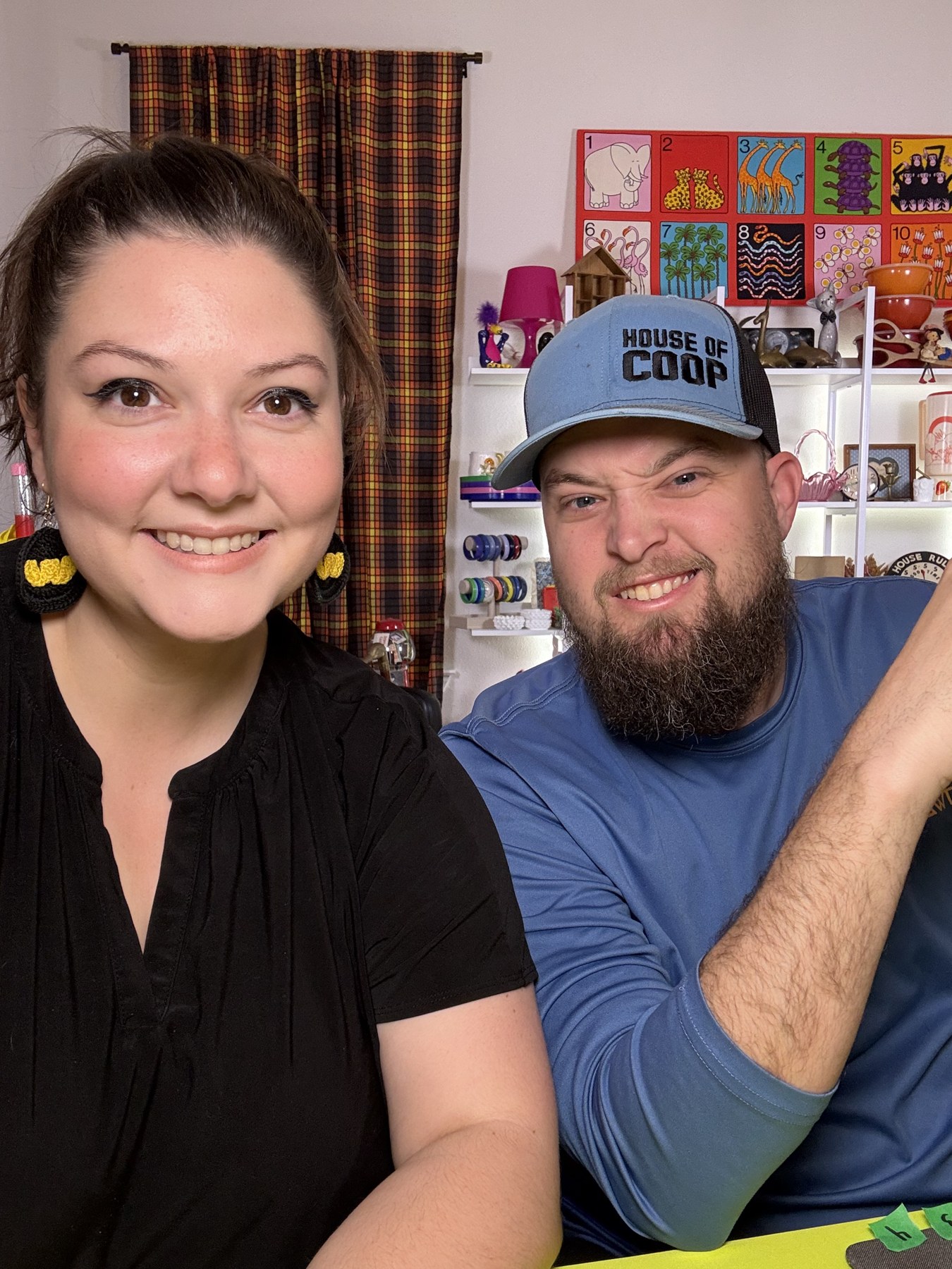 Ashley and Jacob smiling in the studio, with Jacob wearing a blue House of Coop cap