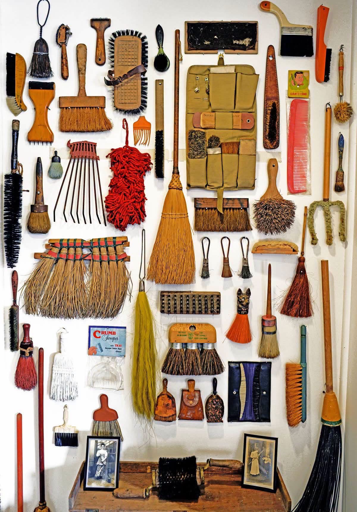 Vintage brushes, brooms and combs displayed together on a white wall
