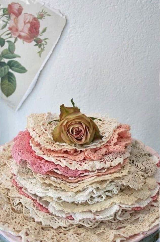 Pink and cream doilies stacked beneath a dried rose