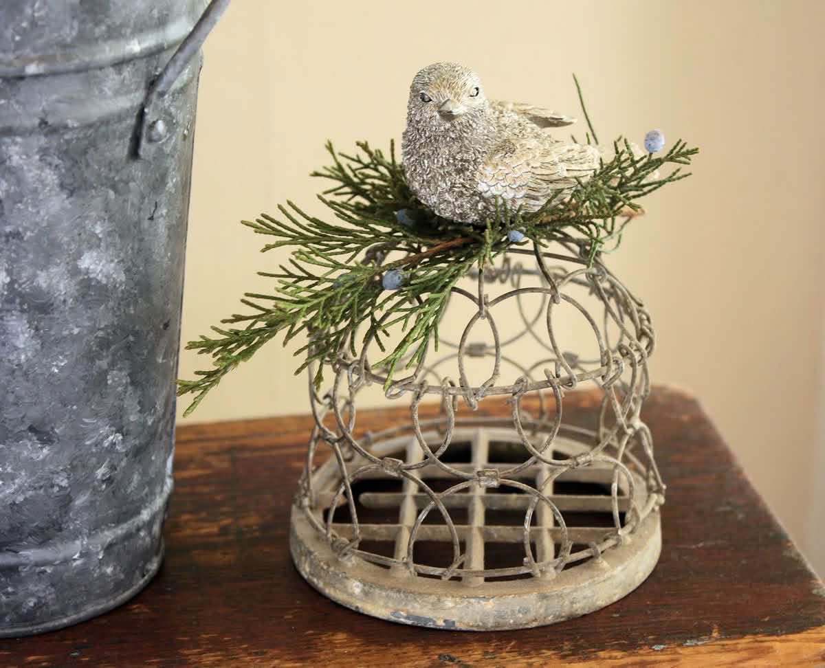 A small bird and evergreen sprigs decorating a wire cage flower frog