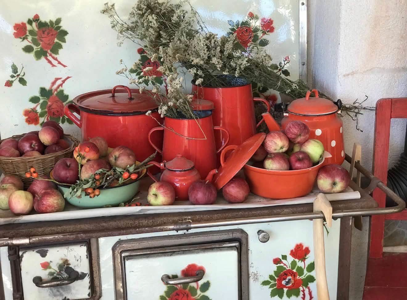 Red enamelware filled with apples on a vintage floral stove
