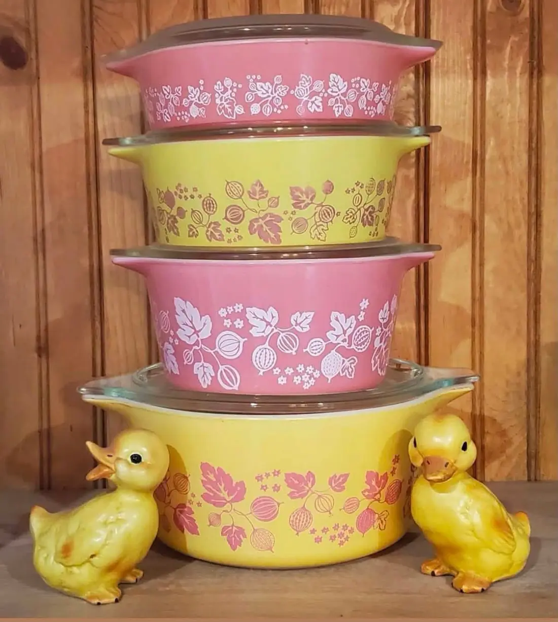 Pink and yellow patterned casseroles stacked beside ceramic ducklings
