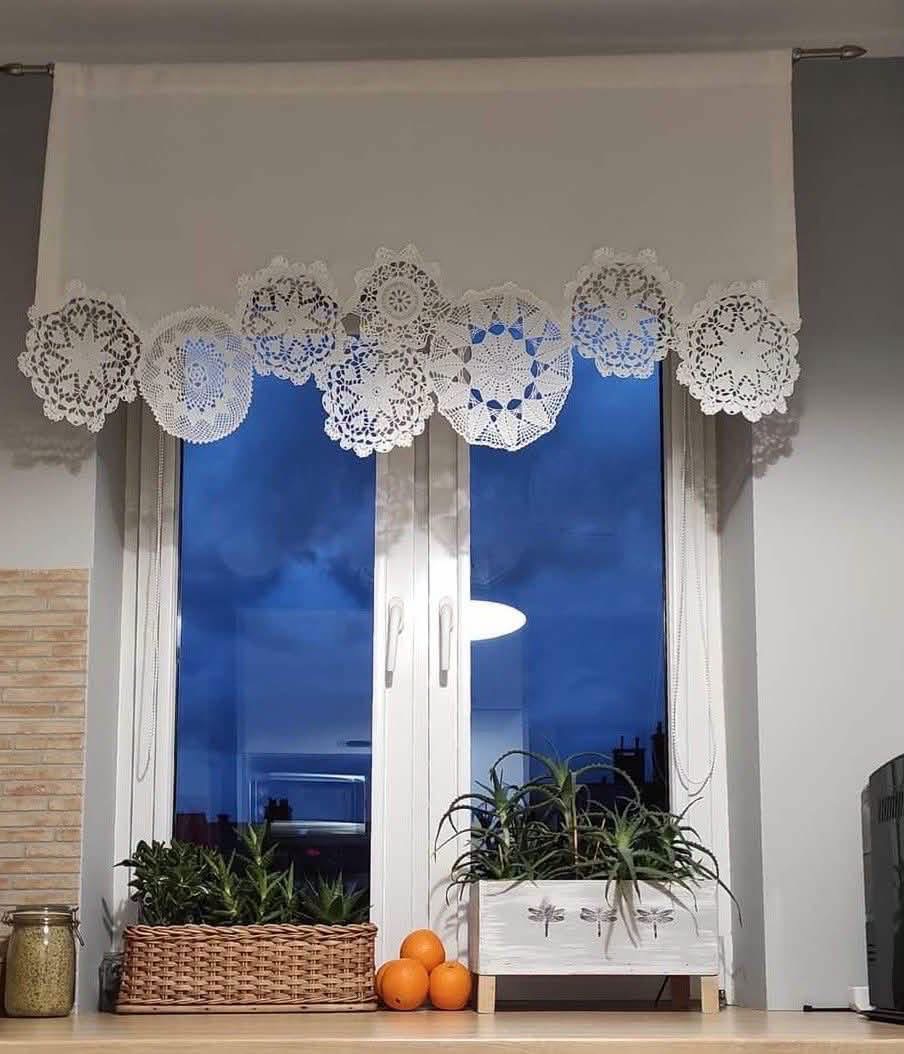 A white window valance edged with overlapping doilies