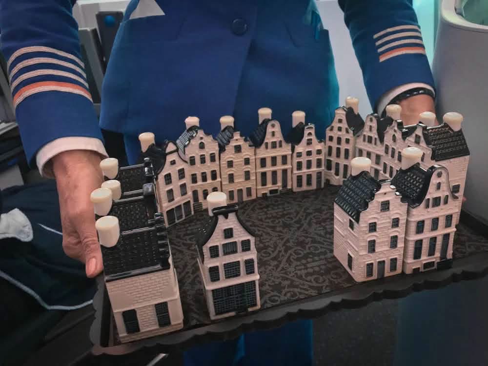 A uniformed airline crew member holding a tray of miniature Delft houses