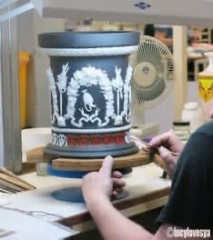 Craftsperson decorating a large blue and white vessel