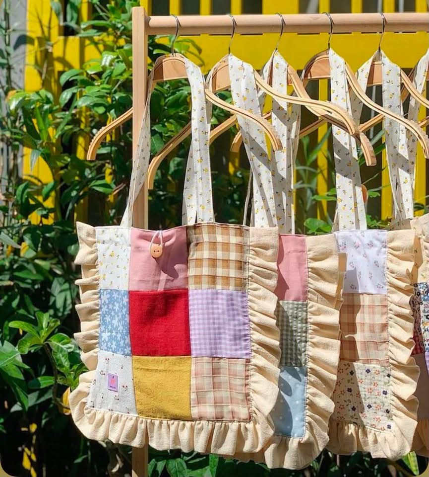 Ruffled patchwork tote bags hanging from wooden hangers