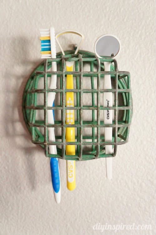 Toothbrushes and dental tools held in a wall mounted green flower frog