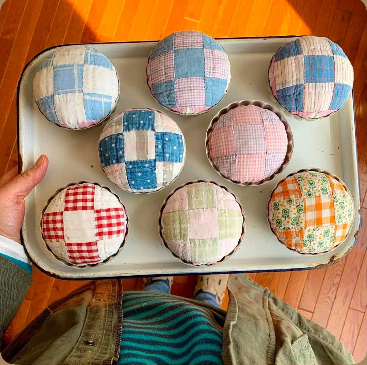 Round patchwork pincushions in metal molds on a tray