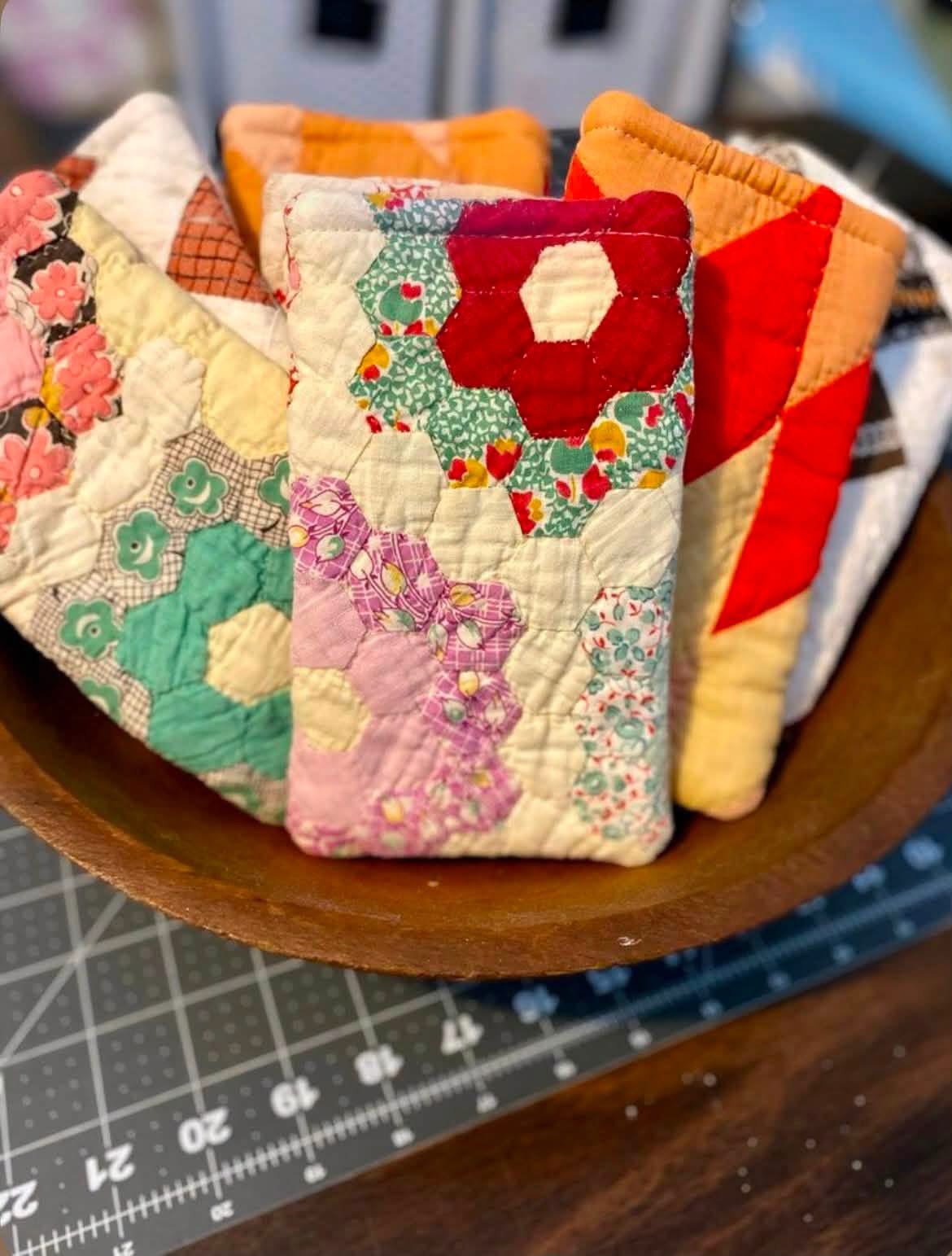 Colorful floral quilted pouches displayed in a wooden bowl