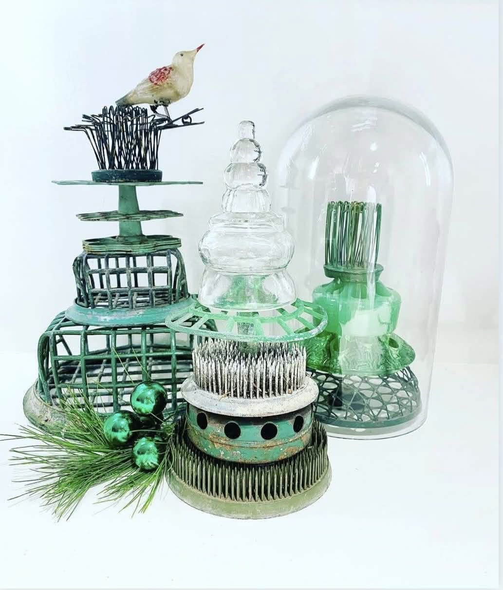 Green and silver flower frogs stacked with glass cloches and holiday ornaments