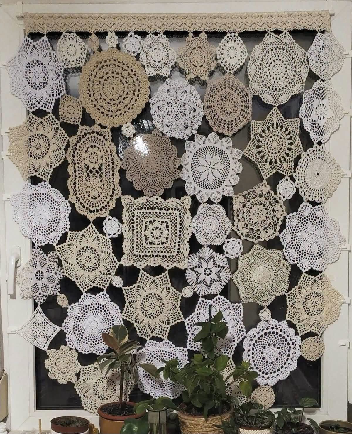 White and cream doilies joined into a window curtain above houseplants