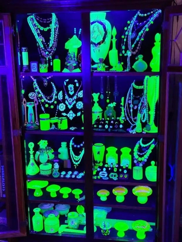 Vintage glass and jewelry glowing green in a display cabinet