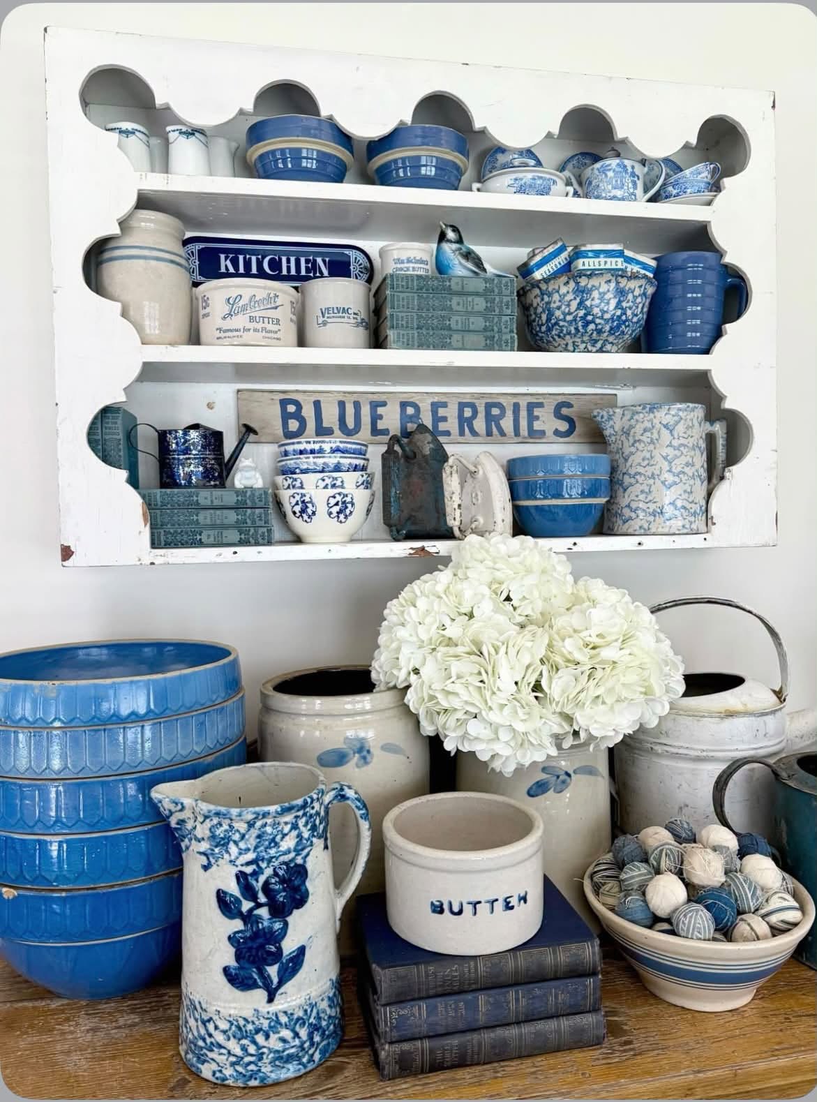 Blue and white bowls, pitchers, and vintage kitchen pieces on white shelves