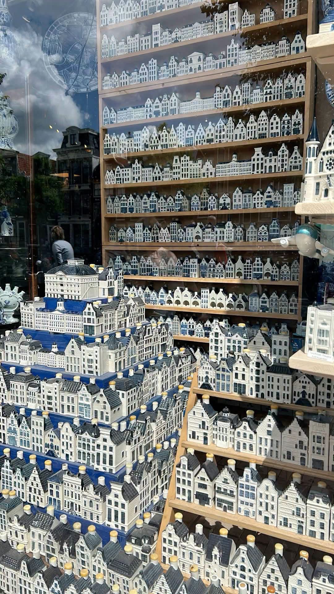 A tall shop window filled with shelves of miniature blue and white houses