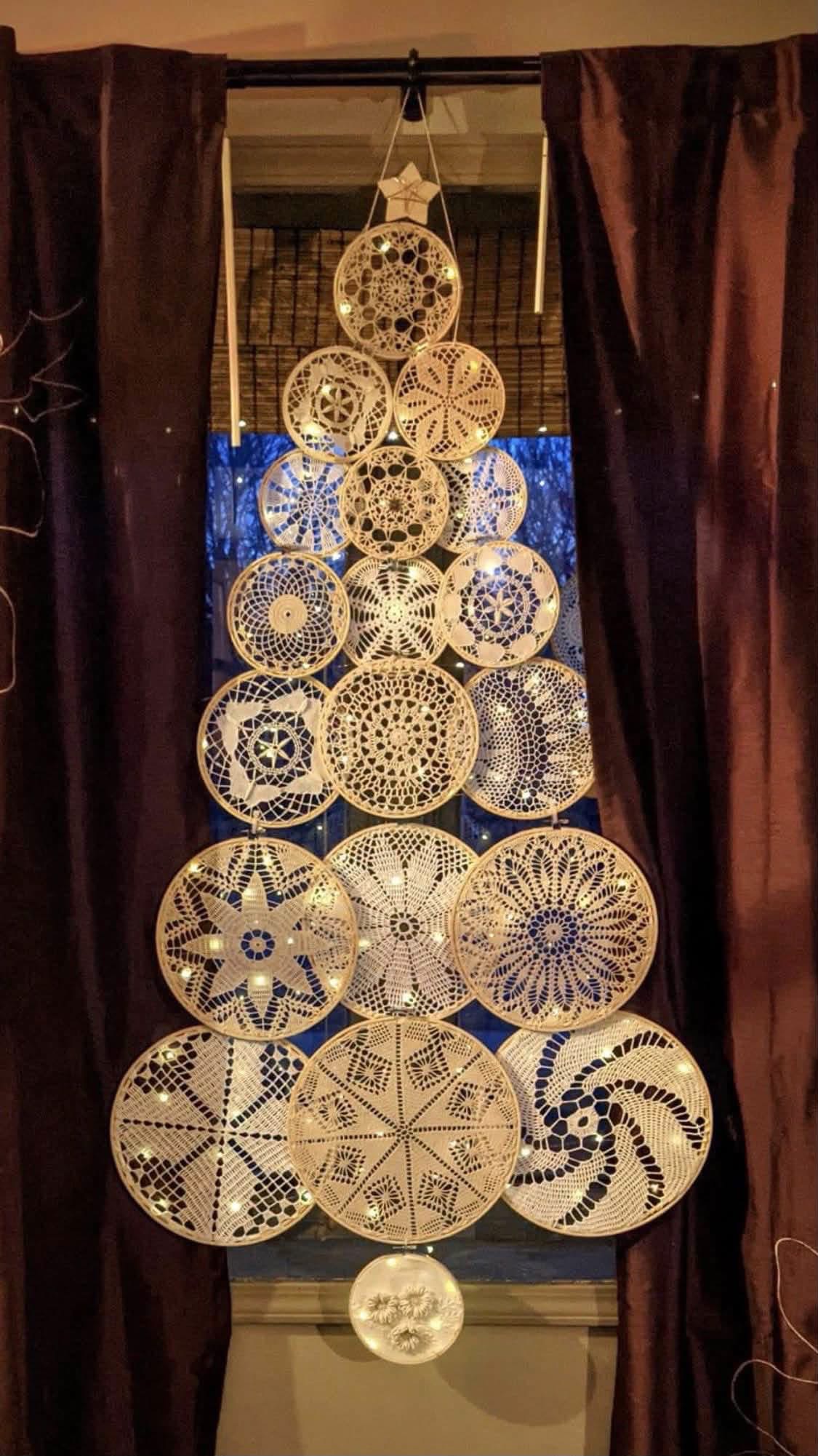 Lighted doily hoops arranged as a Christmas tree in a window