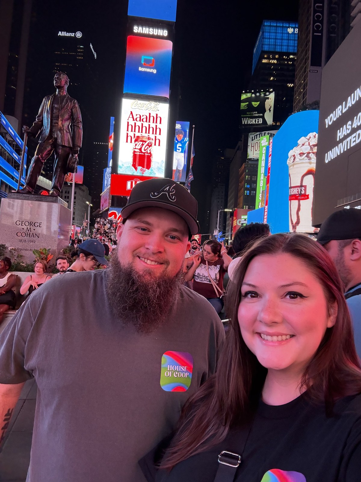 Ashley and Jacob smiling together beneath bright city signs at night