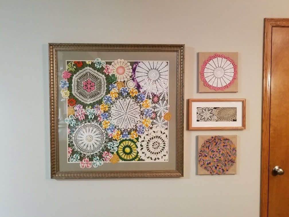 Colorful doilies arranged in a large frame beside smaller textile pieces