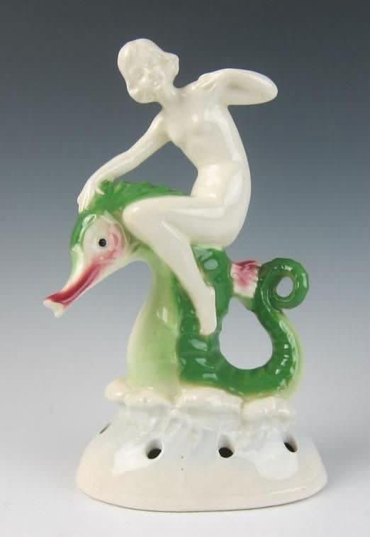 A ceramic flower frog featuring a figure riding a green seahorse
