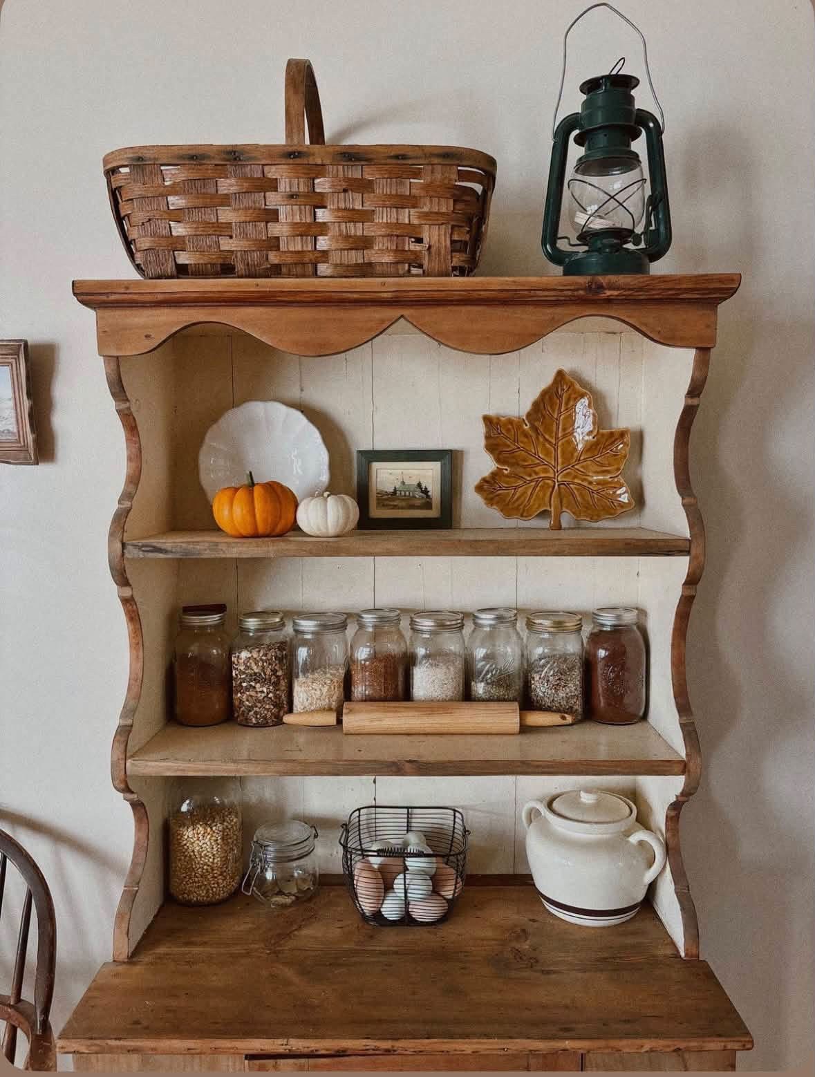 Rustic kitchen hutch with glass jars and small pumpkins