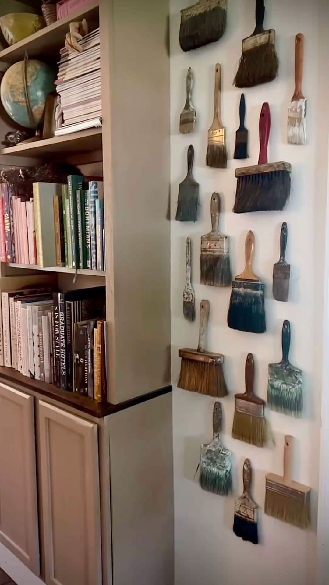 Vintage paint brushes displayed beside a bookshelf