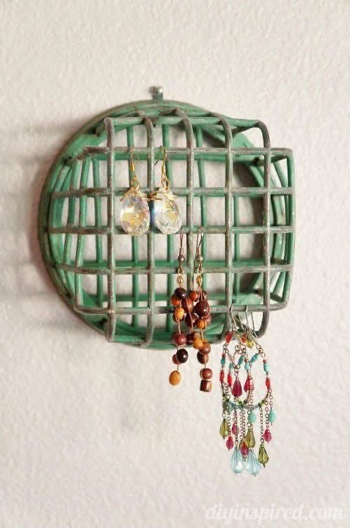 Earrings hanging from a green cage flower frog mounted on a wall
