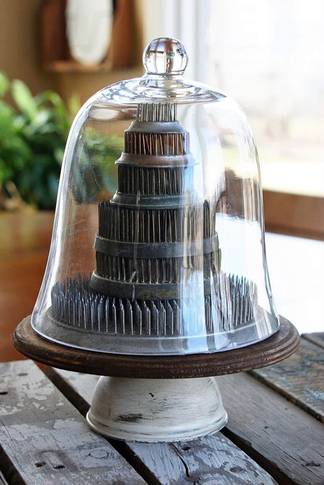 A tower of pin flower frogs beneath a glass cloche