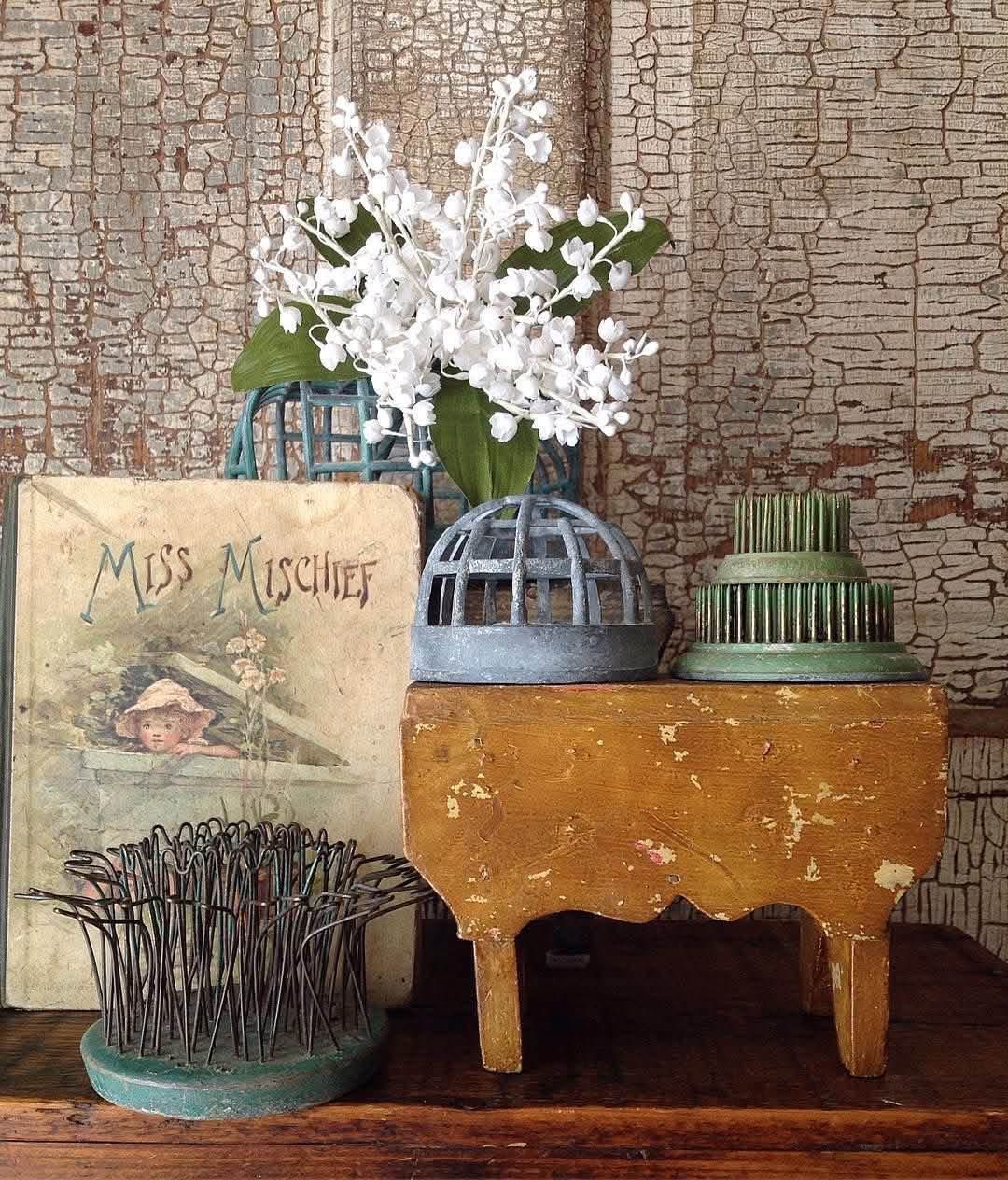 Metal flower frogs displayed with white flowers and a vintage book