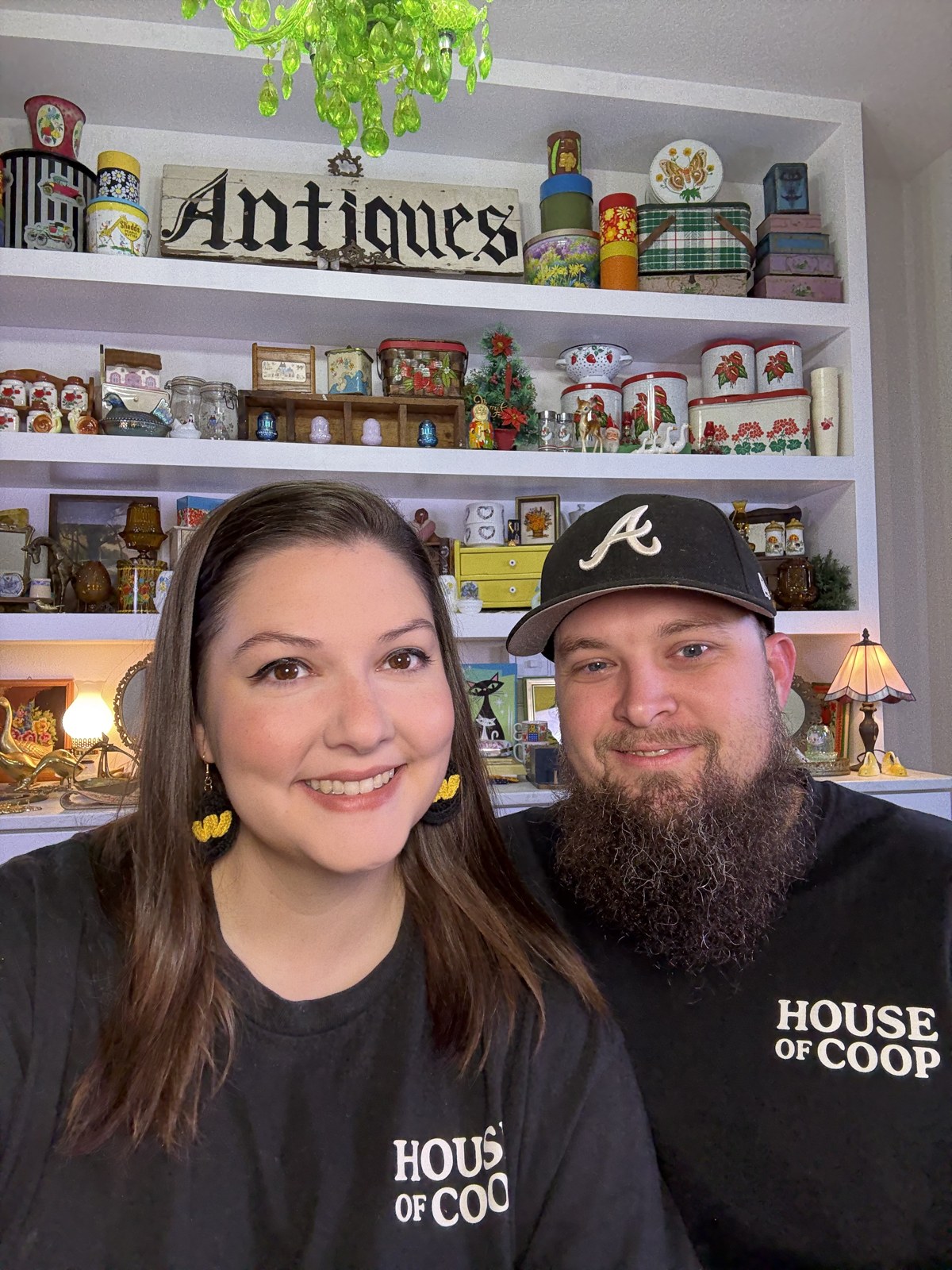 Ashley and Jacob in black House of Coop shirts in front of their vintage shelves