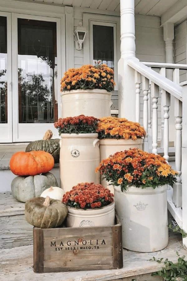 Porch display of chrysanthemums and pumpkins in stoneware crocks