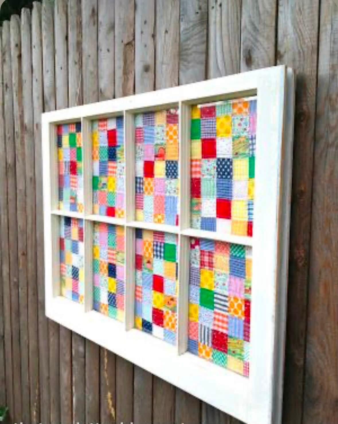 Colorful patchwork displayed in a white window frame