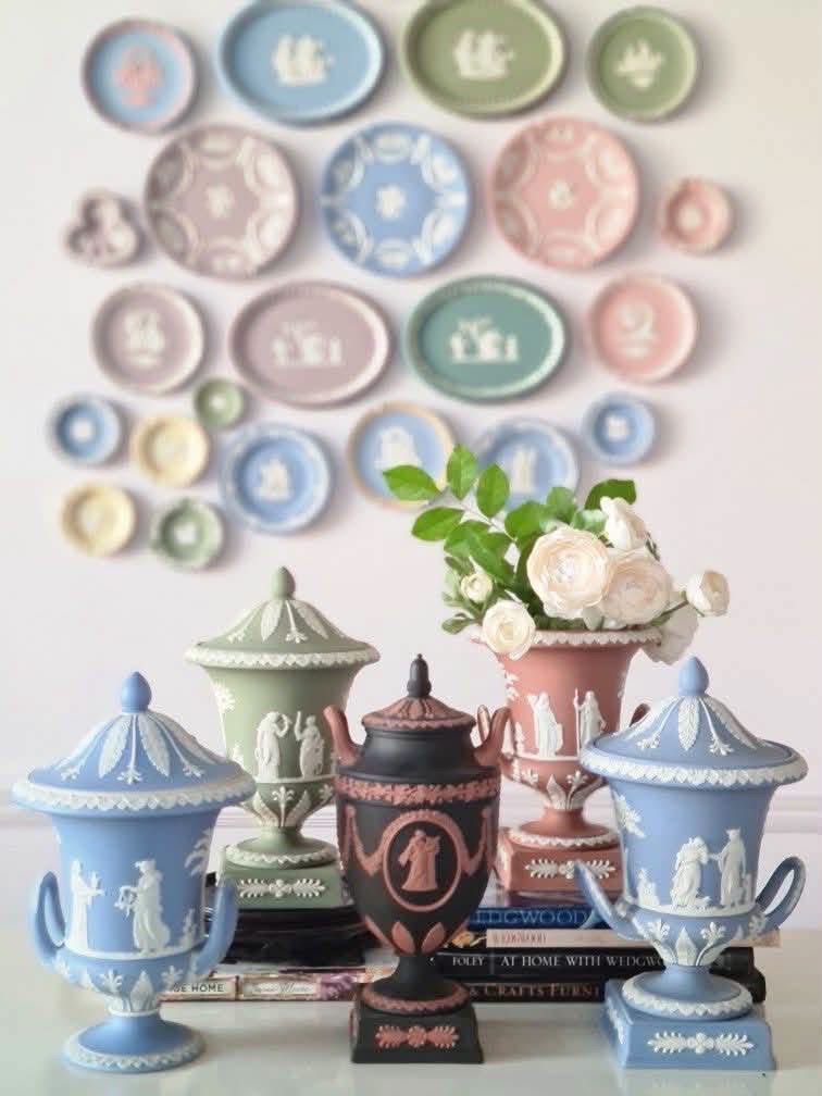 Blue, green, pink and black relief-decorated urns before a display of plates