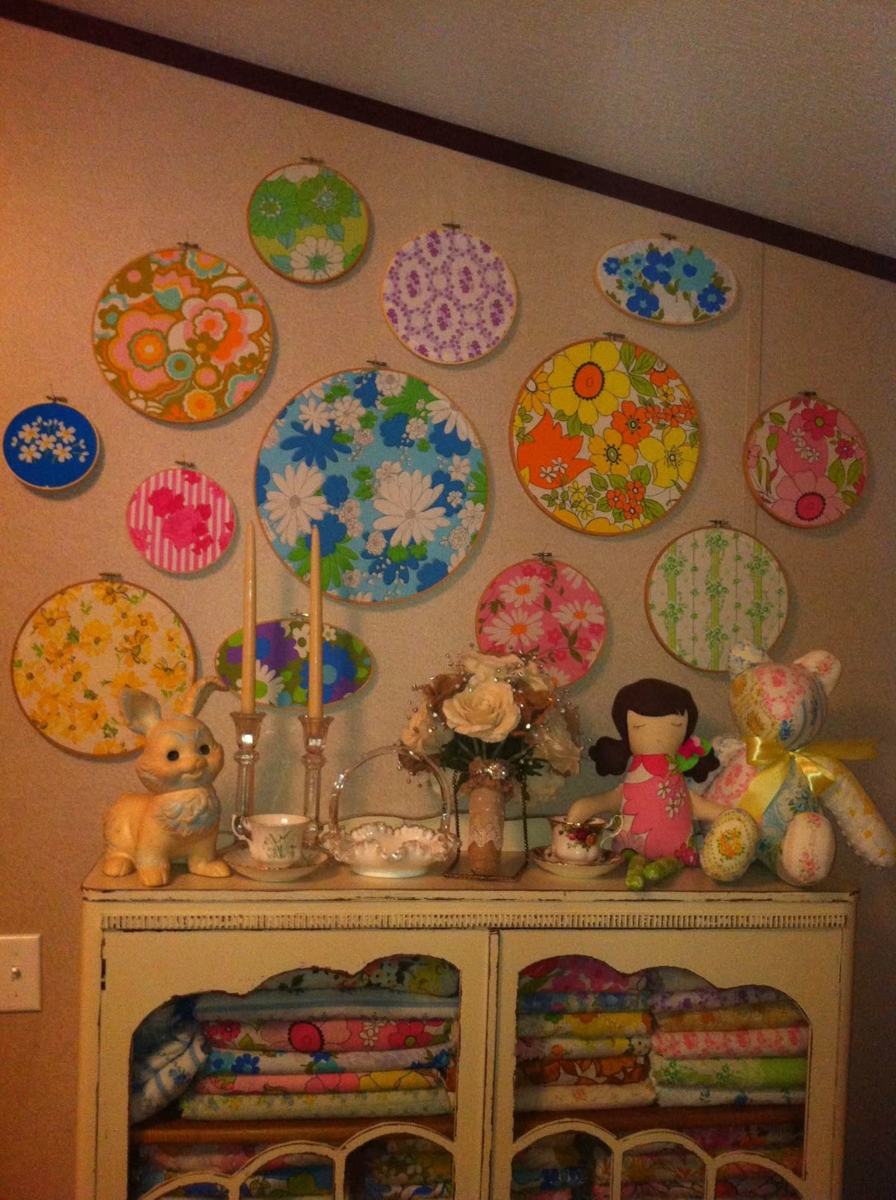 Floral fabrics displayed in embroidery hoops above a cabinet