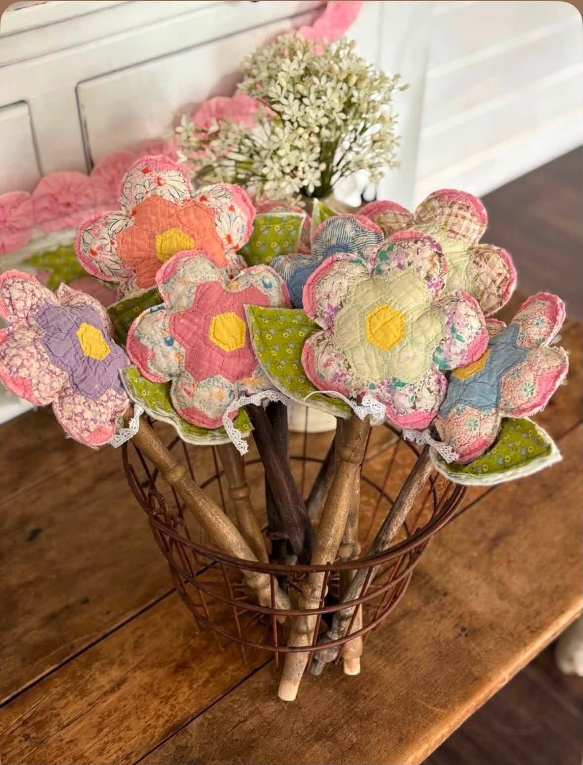 Pastel quilted flowers on wooden stems in a wire basket