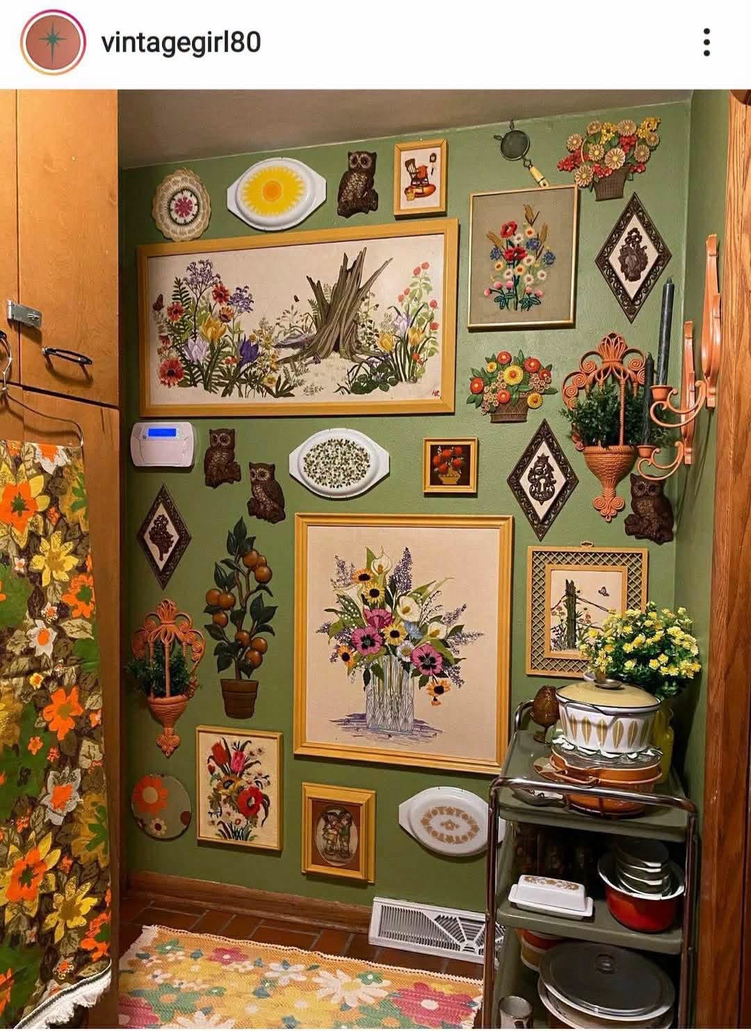 Floral needlework and vintage ornaments on a green wall, credited to vintagegirl80