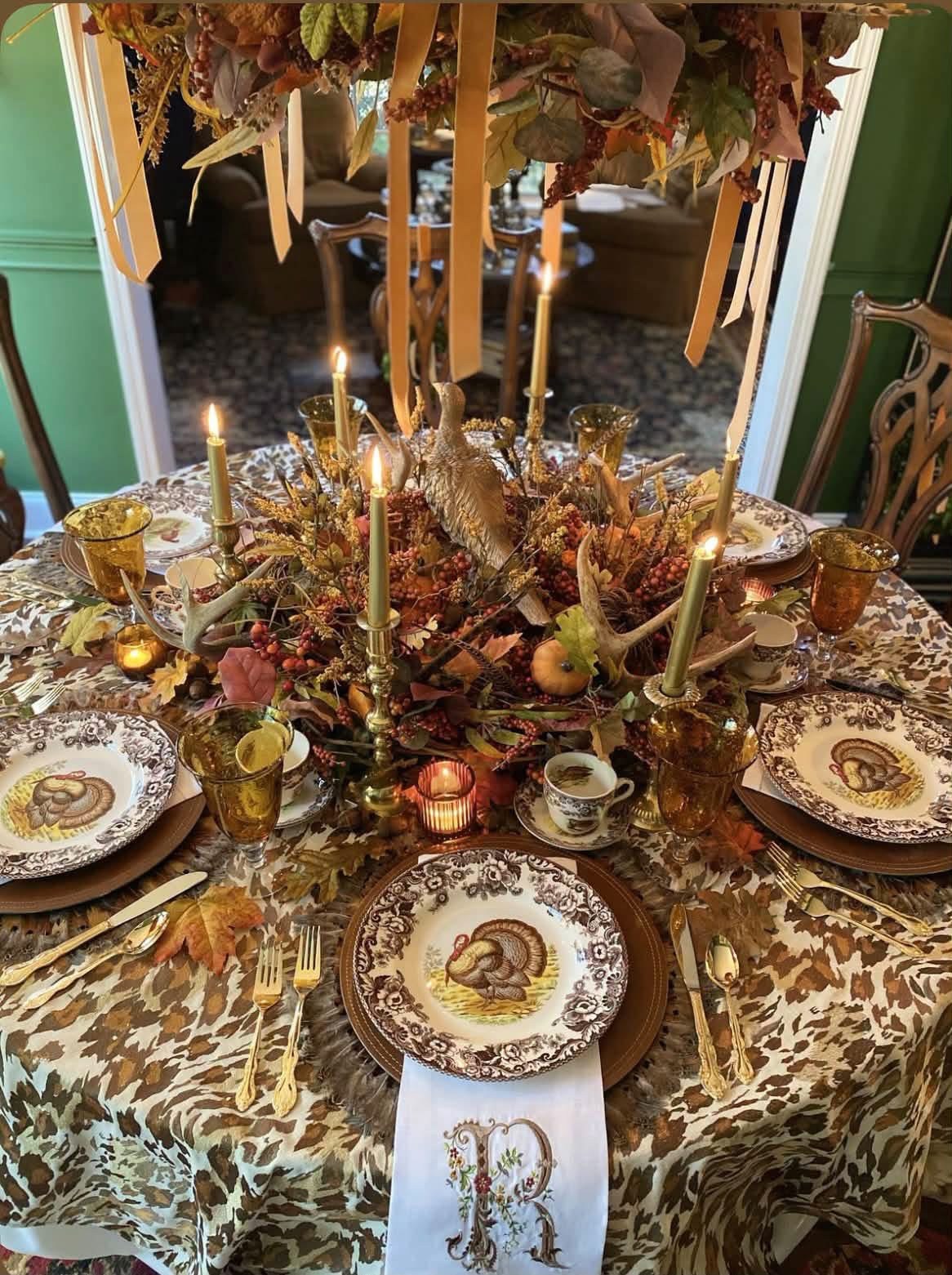 Autumn table with turkey plates, amber glasses, and candles