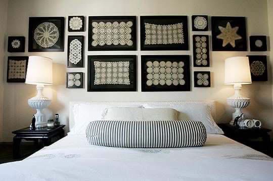 Black framed lace pieces displayed above a white bed