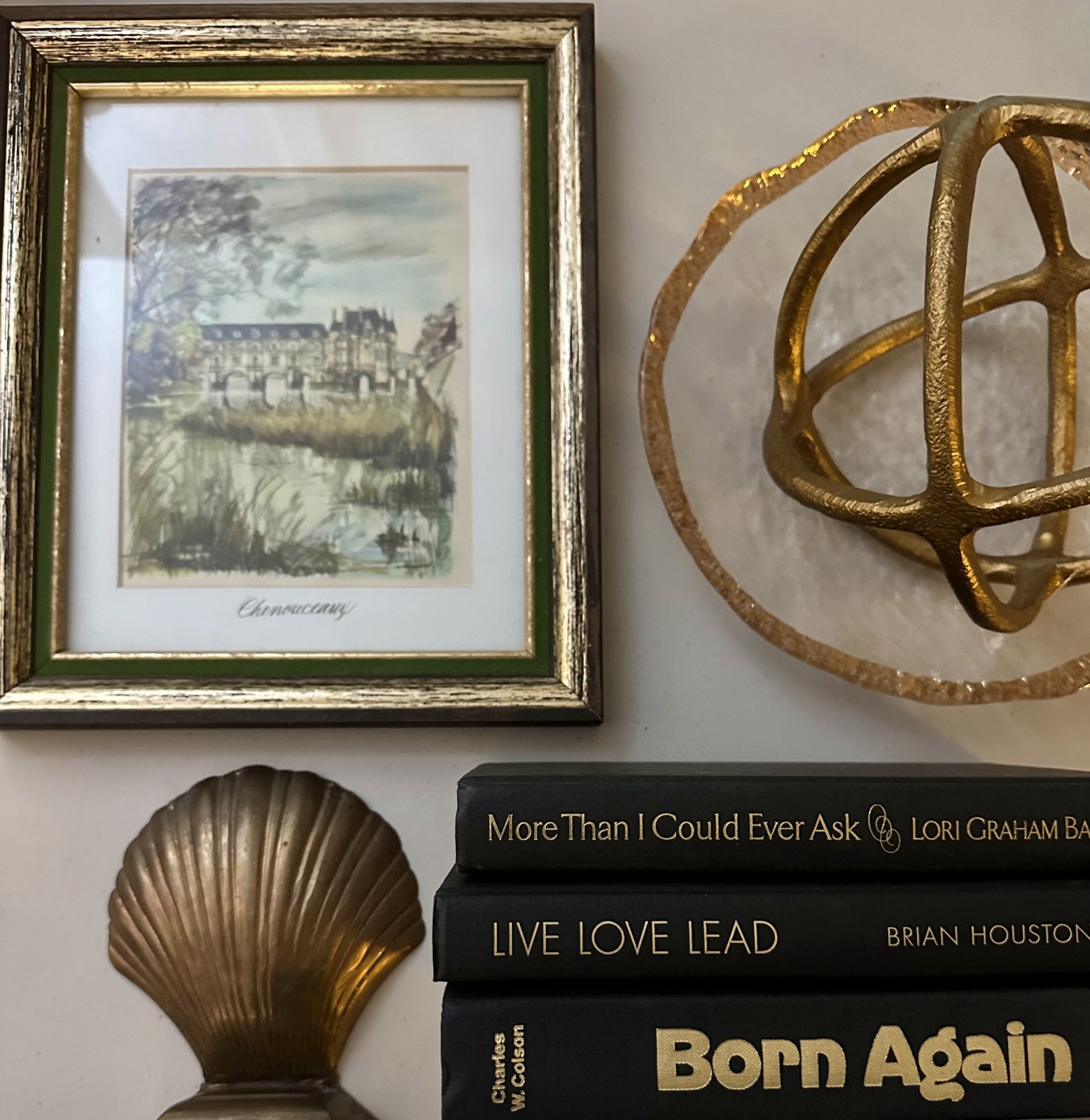 Framed artwork, a brass shell and books from the home-thrifting collection