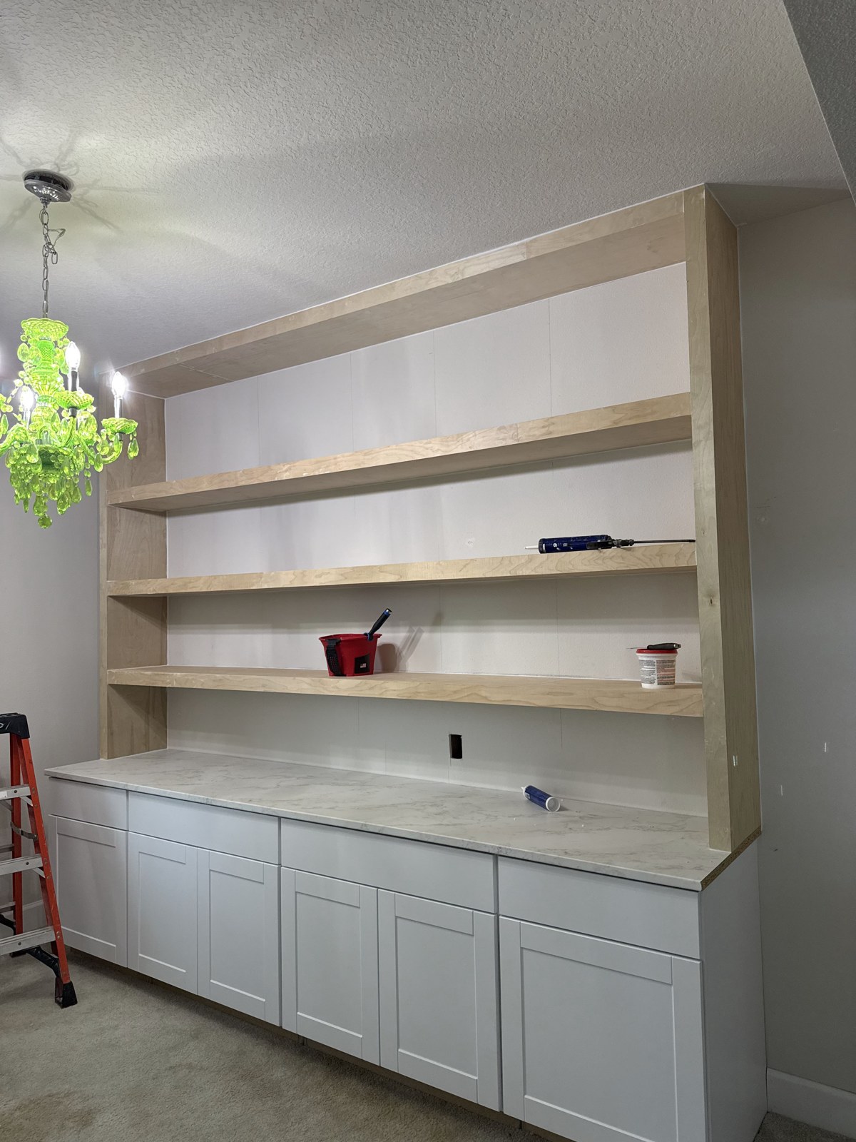 The new custom shelving above white cabinets during installation