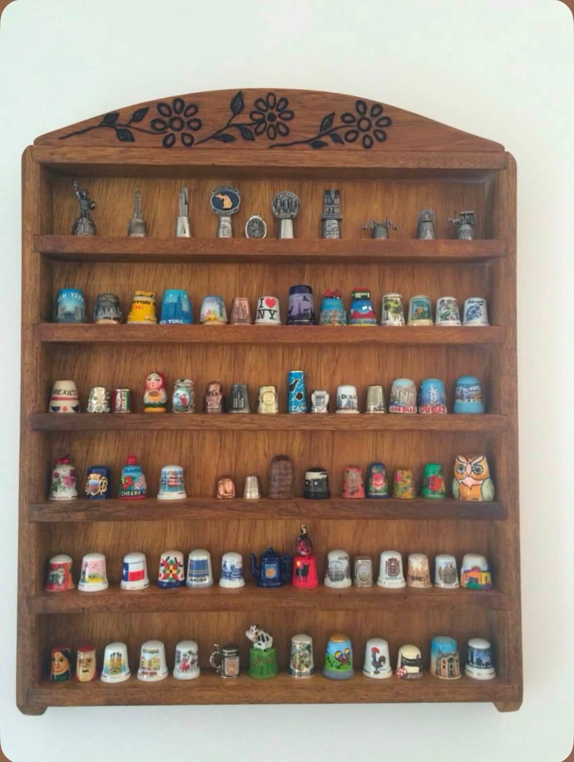Souvenir thimbles displayed on a wooden wall shelf