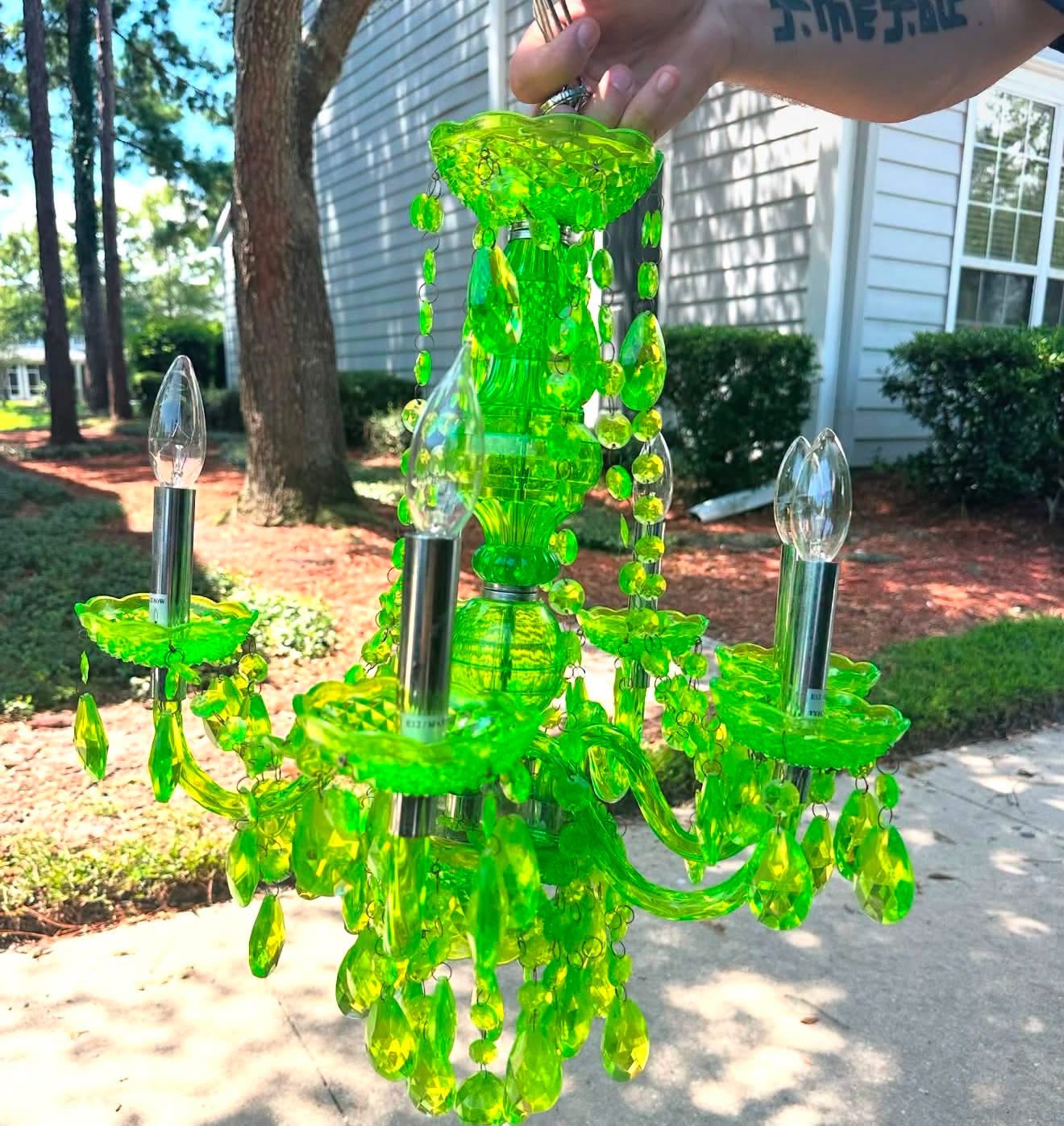 Lime green acrylic chandelier held outdoors on the day House of Coop found it