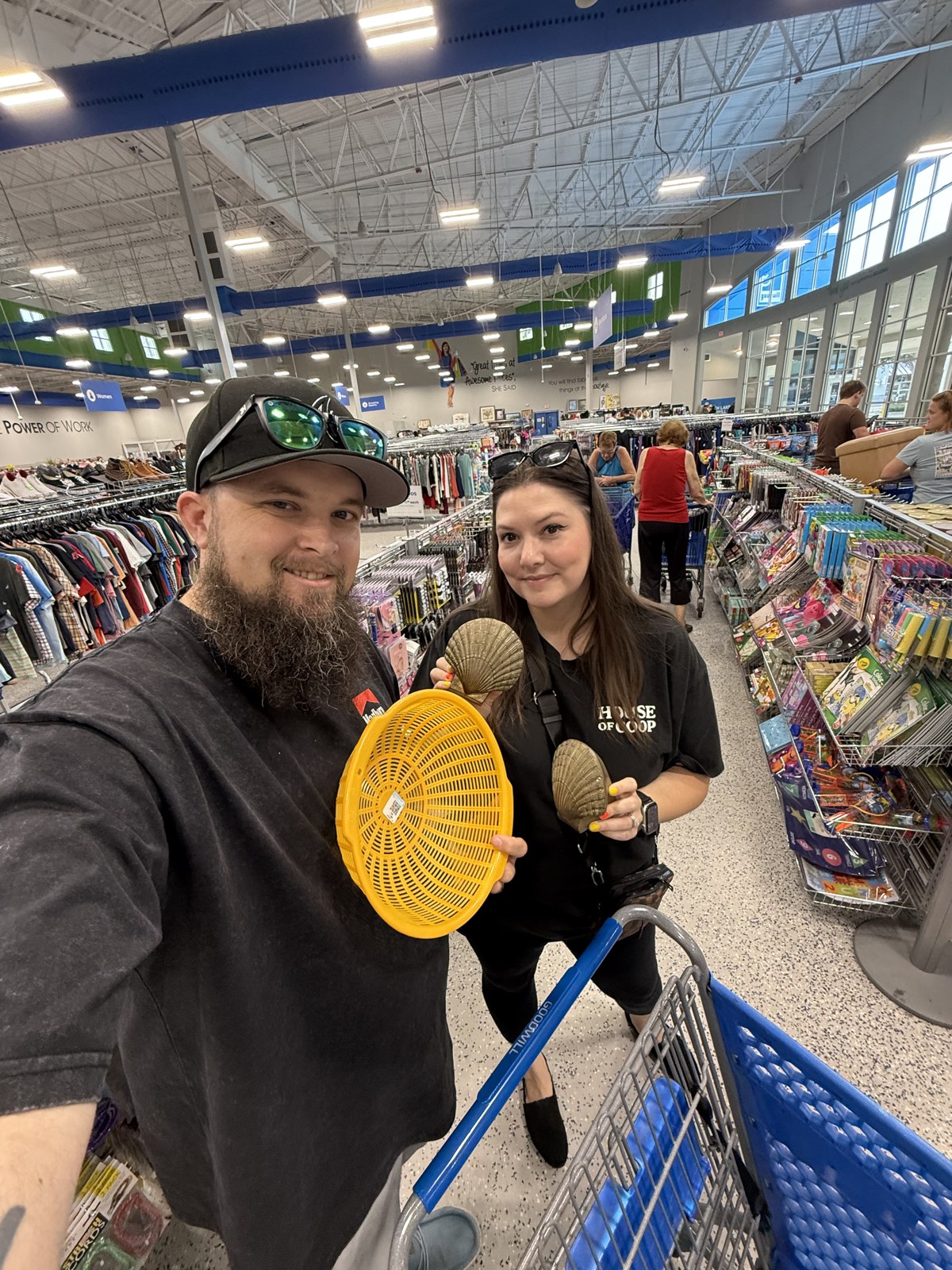 Ashley and Jacob browsing a thrift store with a shopping cart and yellow fan
