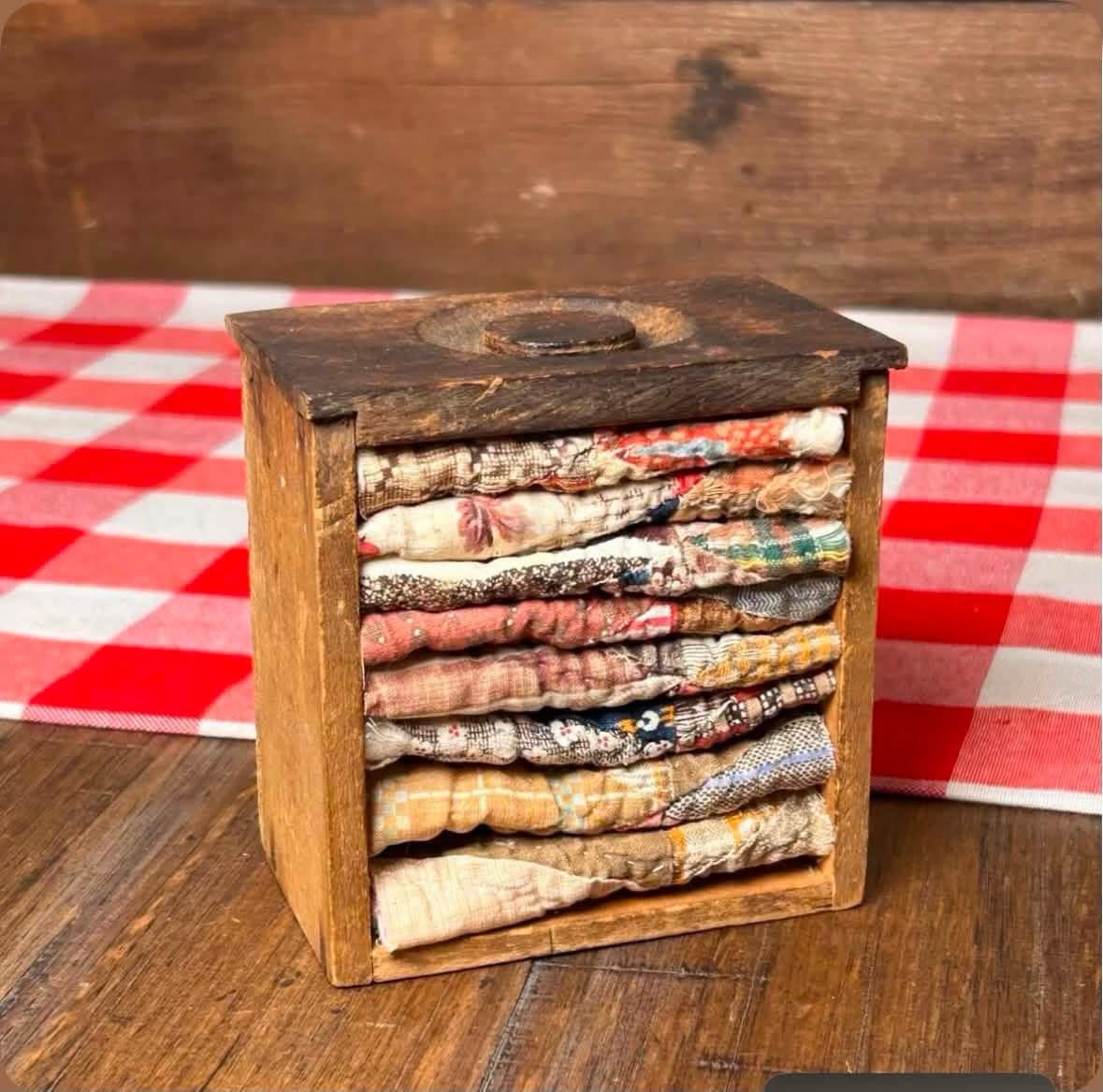 Folded quilt pieces displayed in a small wooden box