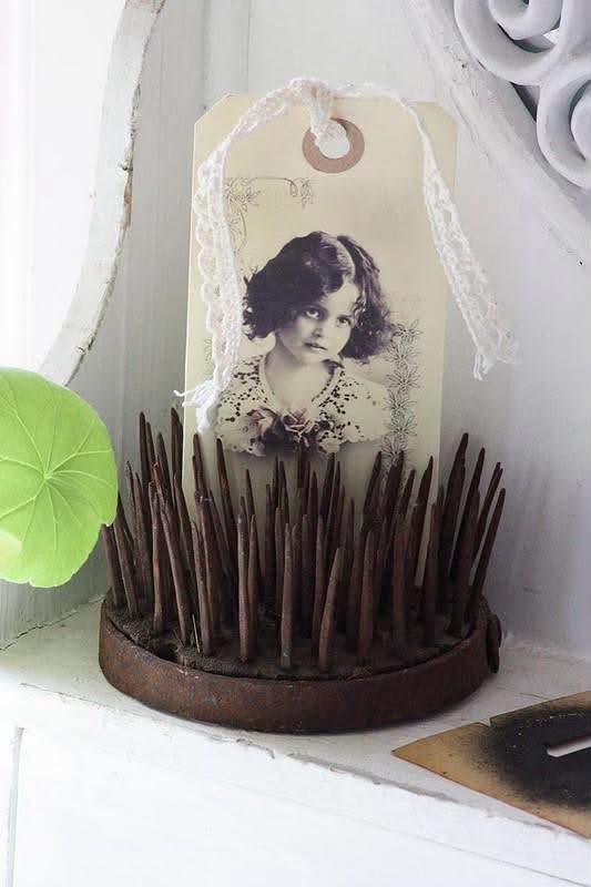 A vintage portrait tag displayed in a rusty pin flower frog