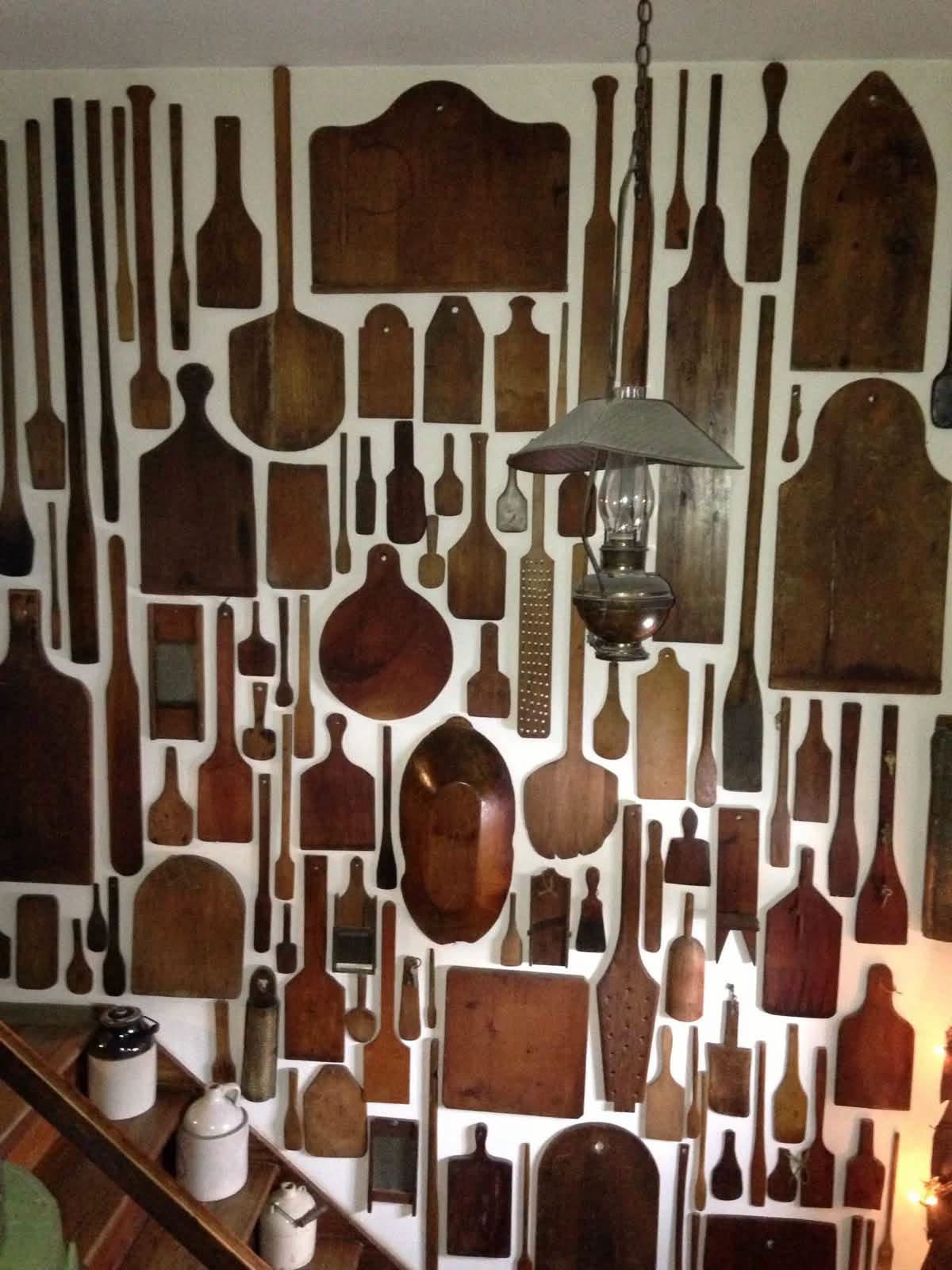 Wooden cutting boards, paddles and spoons arranged around a hanging oil lamp