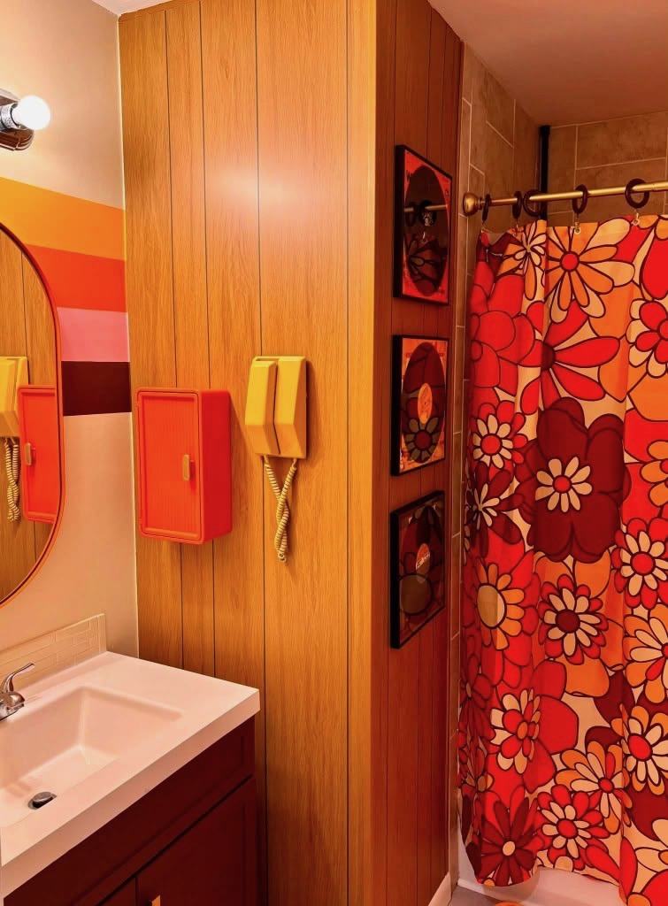 Orange bathroom with a bold red floral shower curtain