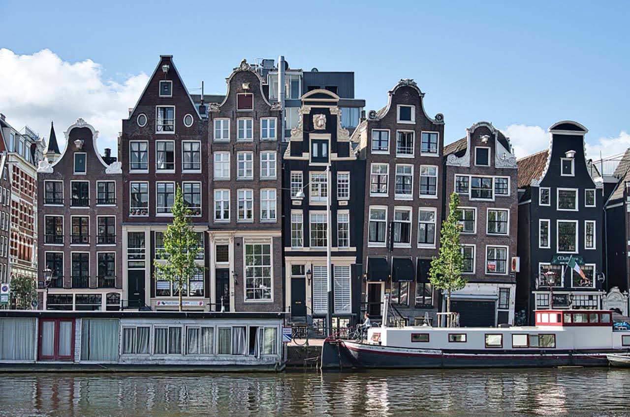 Gabled Amsterdam canal houses and boats beside the water